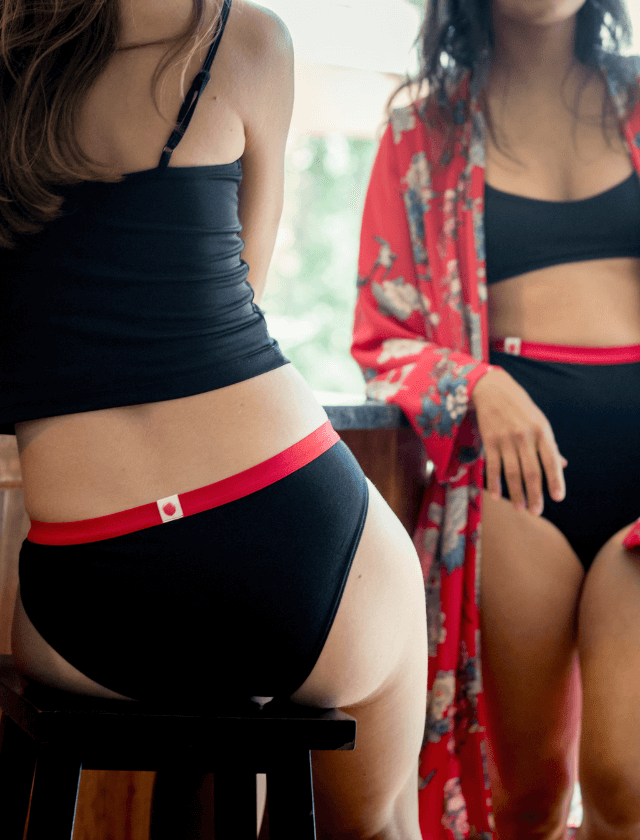 Culotte menstruelle bikini noire avec élastique rouge, vendues avec trois serviettes amovibles pour flux légers à flux abondants.